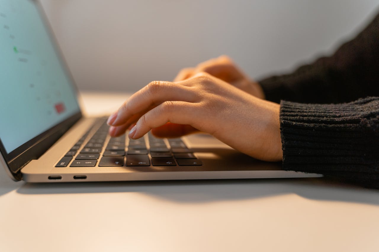 Close-up view of hands typing on a laptop keyboard, illustrating the concept of remote work and technology.